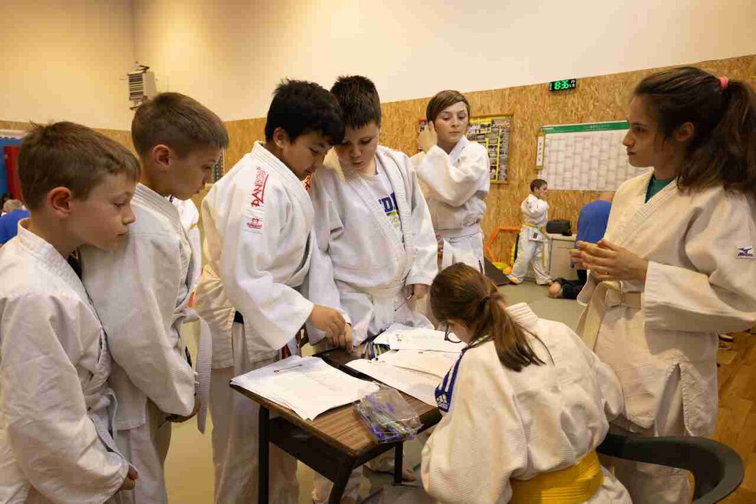 Genitori che osservano una lezione di judo dei propri figli a bordo tatami