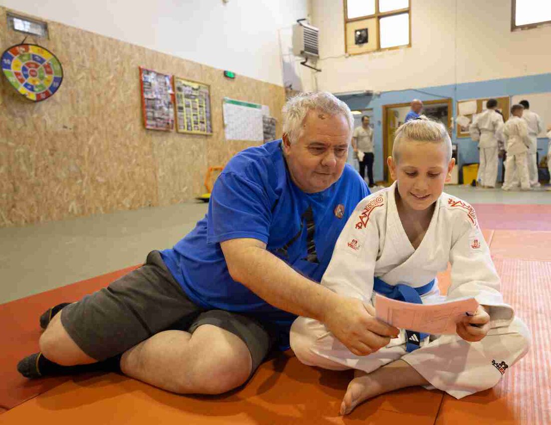 Insegnante di judo che spiega una tecnica a un gruppo di allievi in dojo